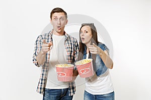 Young couple, woman and man in 3d glasses and casual clothes watching movie film on date, holding buckets of popcorn