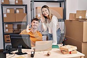 Young couple working at small business ecommerce doing ok sign with fingers, smiling friendly gesturing excellent symbol