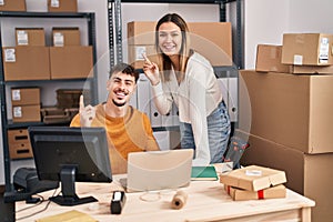 Young couple working at small business ecommerce smiling happy pointing with hand and finger to the side