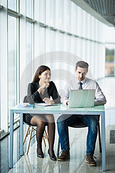 Young couple working together on a laptop in the office. Teamwork concepts.