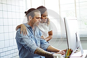 Young couple working together at small office with desktop computers and documents