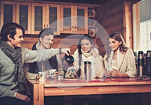 Young couples drinking hot tea in winter cottage
