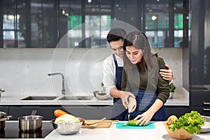 Young couples are helping to chop vegetables in the kitchen. Asian couple cooking together at the kitchen