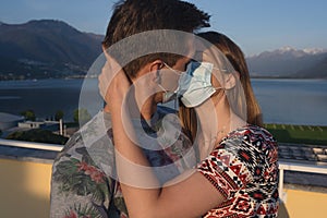 Young couples wear a protective mask and kiss on the terrace of their home