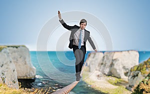 Young courageous businessman is walking on rope photo