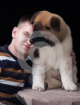 A young courageous man with a shaggy puppy, the dog licks the man`s face