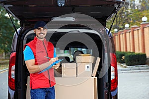 Young courier checking amount of parcels in delivery van