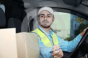 Young courier checking amount of parcels in van