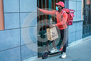 Young courier man holding food delivery bag ringing the doorbell - Focus on face
