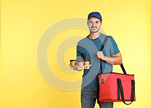 Young courier with thermo bag and drinks on color background, space for text