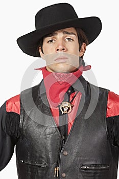 Young cowboy in black leather vest against white background