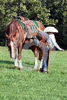 Young cowboy mounting horse photo