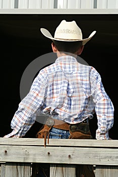 Young cowboy sitting on fence photo