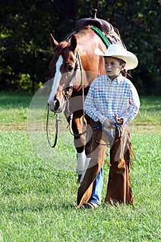 Young cowboy walking horse