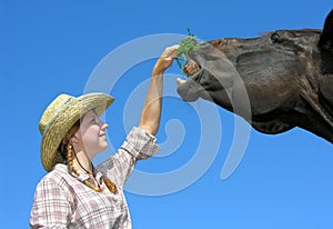 Young cowgirl feeding horse