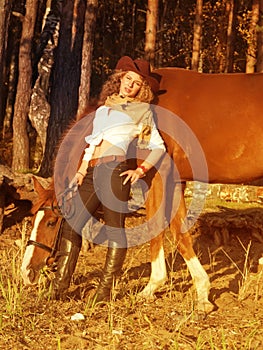 Young cowgirl with her red horse at sunset.