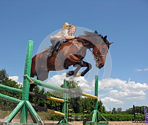 Young cowgirl jumping with chestnut horse