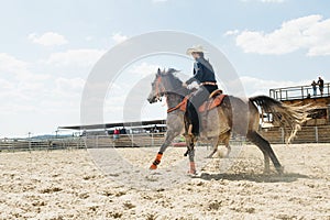 Young cowgirl riding a beautiful paint horse in a barrel racing event at a rodeo.