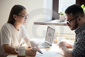 Young coworker looking through papers discussing and negotiating