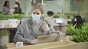 A young coworker is putting a mask on his face