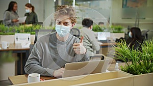 A young coworker is putting a mask on his face