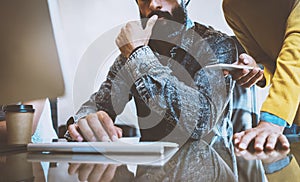 Young coworkers discussing business ideas at workplace.Man working on desktop computer.Woman standing close him and