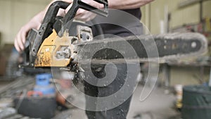 Young craftsman starting powered chainsaw in workshop