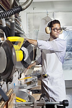 Young craftsman wearing protective gear while using circular saw