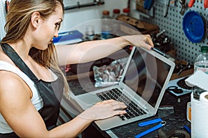 Young craftswoman working using a laptop in the garage