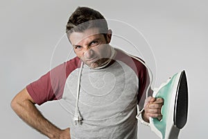 Young crazy desperate and frustrated man doing housework holding iron