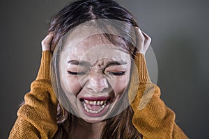 Young crazy desperate and upset Asian Korean woman screaming scared and anxious feeling anger and pain isolated on dark background