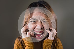 Young crazy desperate and upset Asian Korean woman screaming scared and anxious feeling anger and pain isolated on dark background