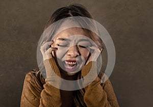 Young crazy desperate and upset Asian Korean woman screaming scared and anxious feeling anger and pain isolated on dark background