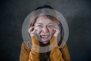 Young crazy desperate and upset Asian Korean woman screaming scared and anxious feeling anger and pain isolated on dark background