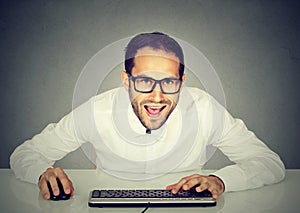 Young crazy looking businessman with glasses typing on keyboard