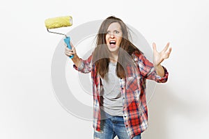 Young crazy loony woman in casual clothes holding paint roller for wall painting and screaming isolated on white