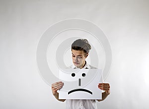 Young crazy man is holding white paper with smile. Unhappy man