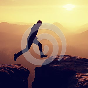 Young crazy man jump on mountain peak. Silhouette of jumping man