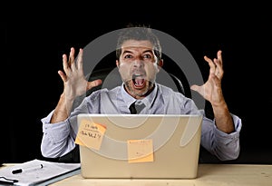 Young crazy stressed businessman screaming desperate working in stress with laptop computer