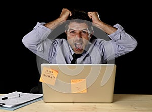 Young crazy stressed businessman screaming desperate working in stress with laptop computer