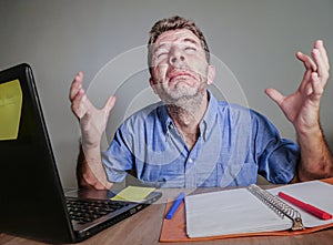 Young crazy stressed and overwhelmed man working messy crying desperate with laptop computer feeling exhausted and frustrated in b