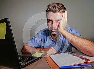 Young crazy stressed and overwhelmed man working messy at office desk desperate with laptop computer feeling exhausted and frustra