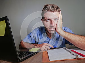 Young crazy stressed and overwhelmed man working messy at office desk desperate with laptop computer suffering depression frustrat