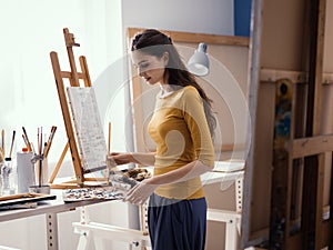 Young creative artist painting in the studio