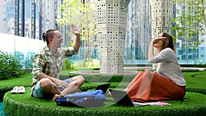 Young creative business people with laptop and digital tablet on green grass in coworking space office