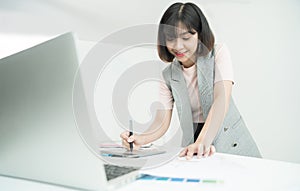 Young creative designer working at office. Graphic designer at work. Color swatch samples.Young female designer using graphics lap