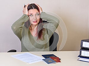 Young creative girl clutched at his head filling the employment contract and employment record, passport and diploma on the table