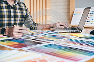 Young creative Graphic designer using graphics tablet to choosing Color swatch samples chart for selection coloring with work too