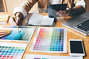 Young creative Graphic designer using graphics tablet to choosing Color swatch samples chart for selection coloring with work too