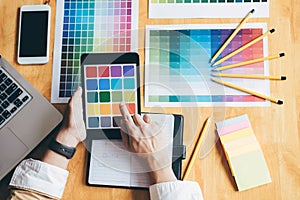 Young creative Graphic designer using graphics tablet to choosing Color swatch samples chart for selection coloring with work too